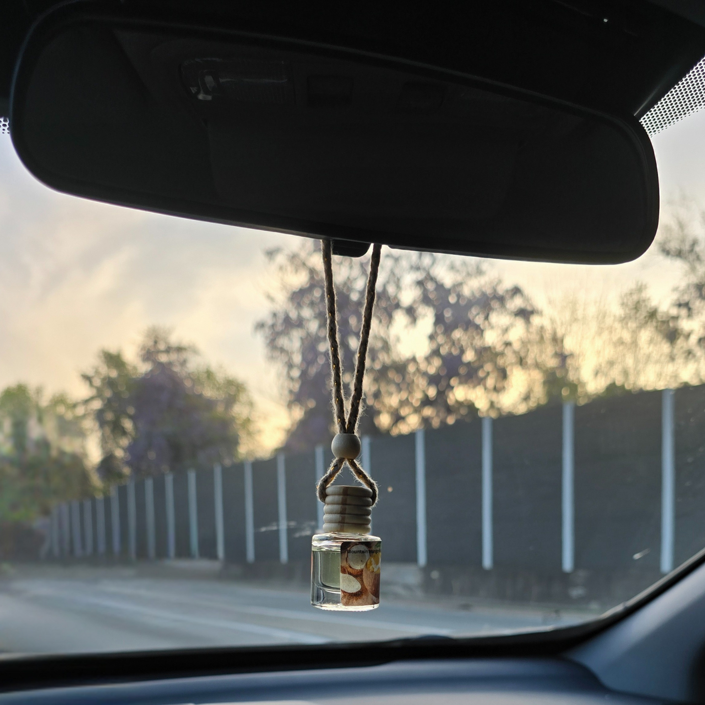 Nanny's Blueberry Pie hanging car air freshener with braided rope and natural fragrance diffuser in a clear glass bottle.