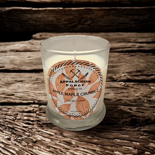 Apple Maple Crumble dye-free soy wax candle in clear glass jar with autumn leaf design label on rustic wooden surface