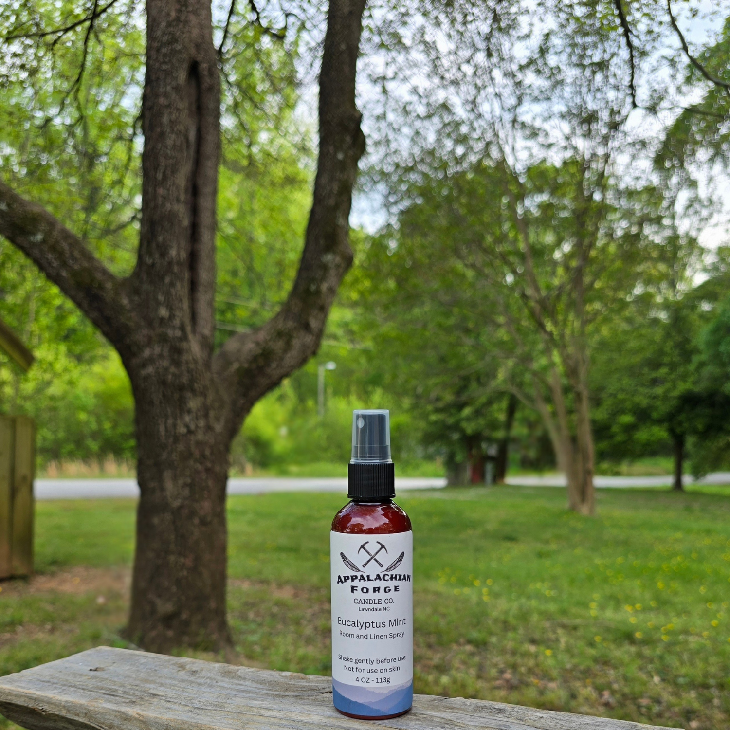 Eucalyptus mint room and linen spray bottle outdoors in a lush green garden.